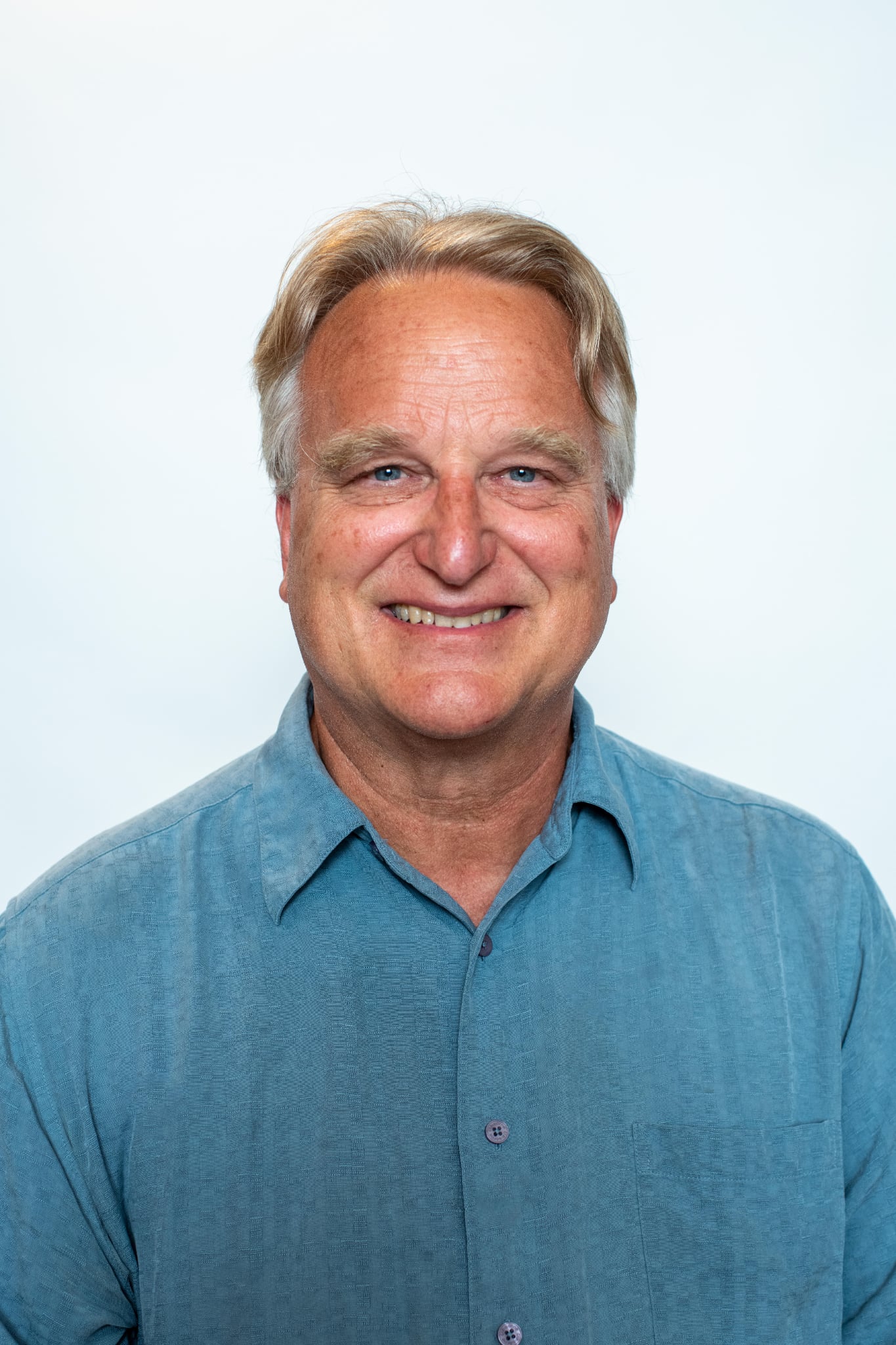 A white man with short light hair and a button down shirt.